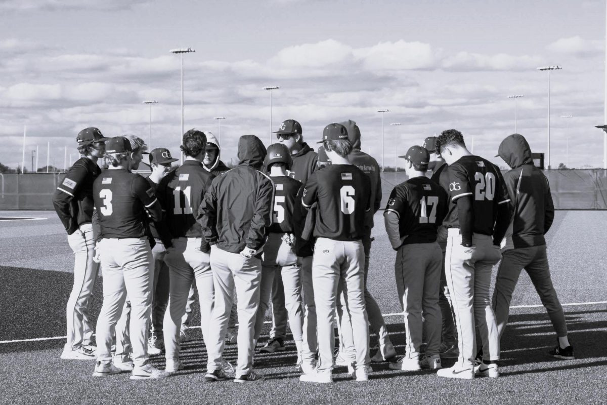 Coach Hughes speaking with the baseball players during a hudle. 